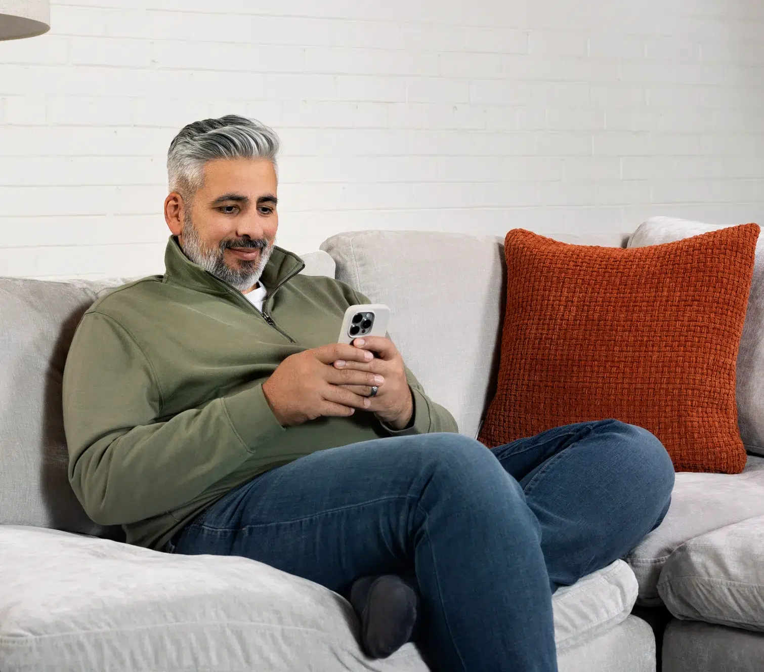 A person sitting on a couch looking at the Felix app on their phone.
