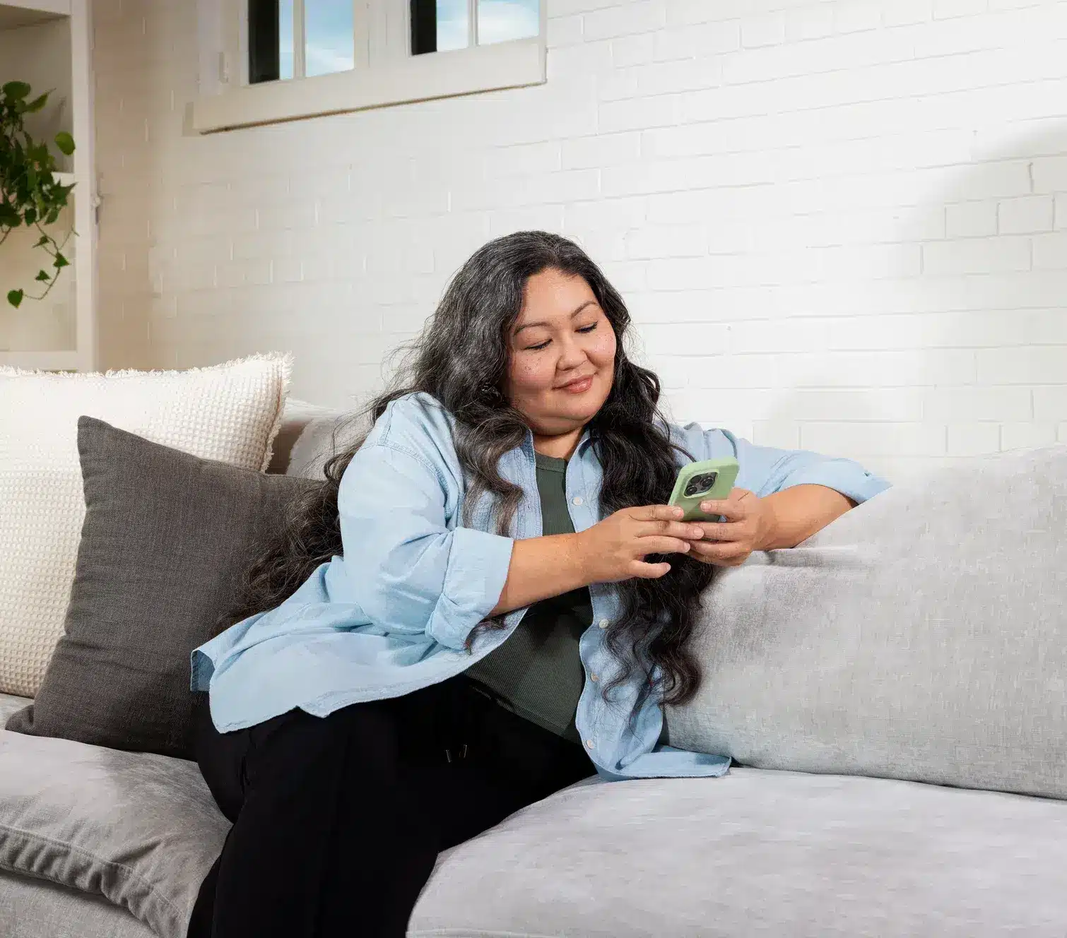 A person sitting on a sofa looking at the Felix app on their phone.